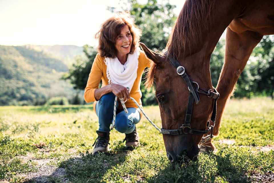 Woman kneeling and smiling at a horse