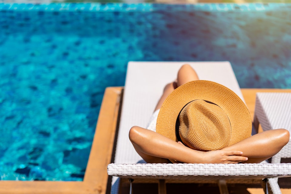 woman in a hat lying by a pool